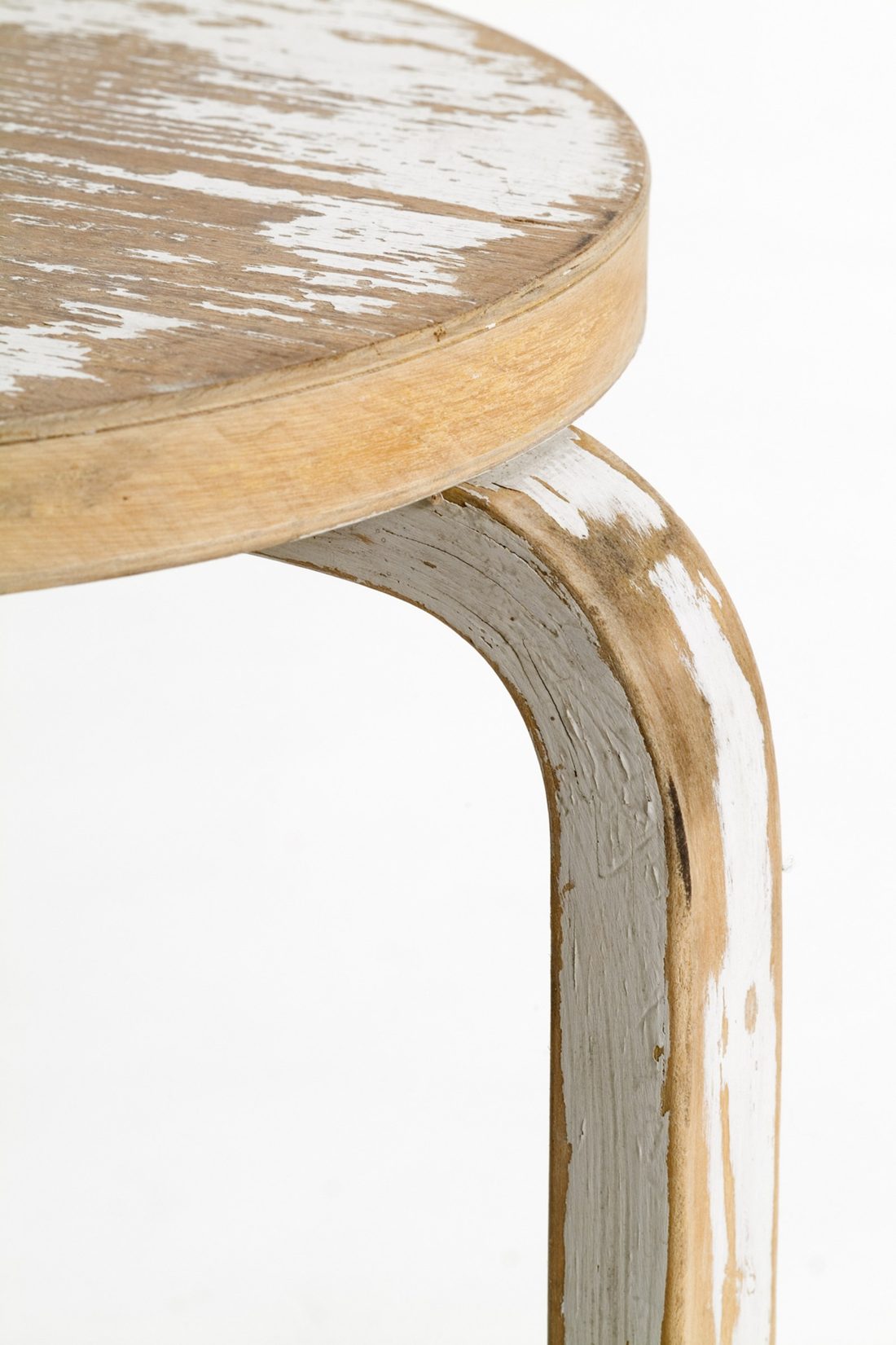 The worn birch seat and leg of a Stool 60, white paint rubbed back to the wood